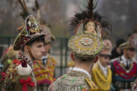 People wearing communist era military uniforms, decorated with colorful items, take part in a parade showcasing winter traditions from the northeast of the country in Bucharest, Romania, Sunday, Dec. 18, 2022. (AP Photo/Vadim Ghirda)