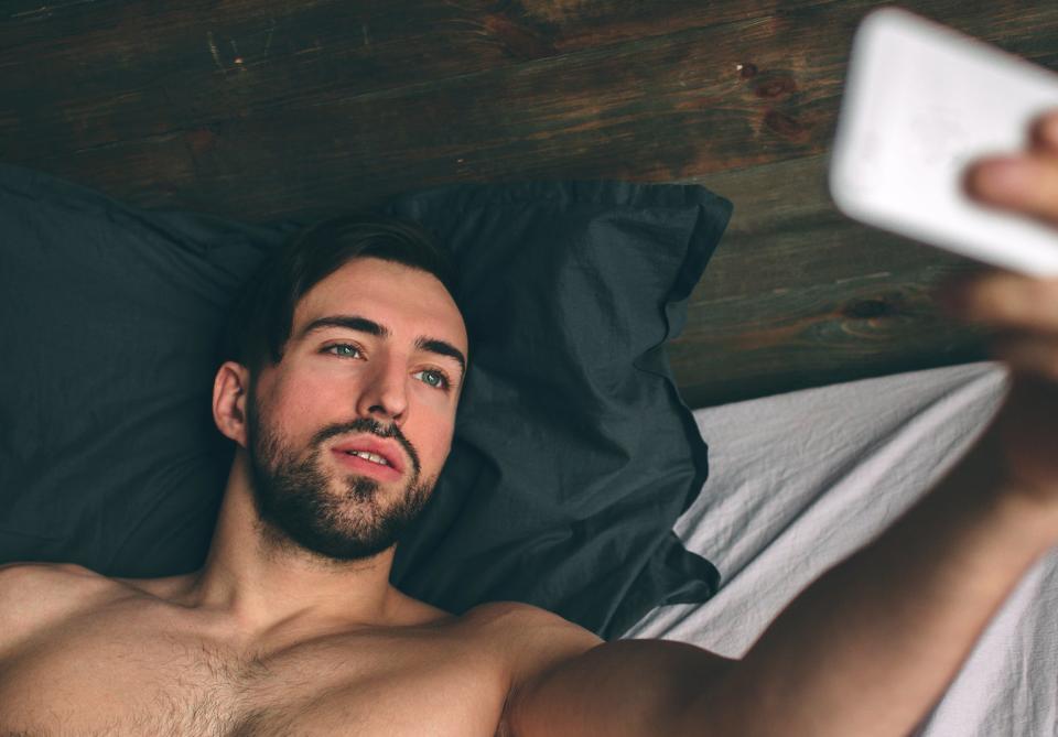 A shirtless man takes a selfie