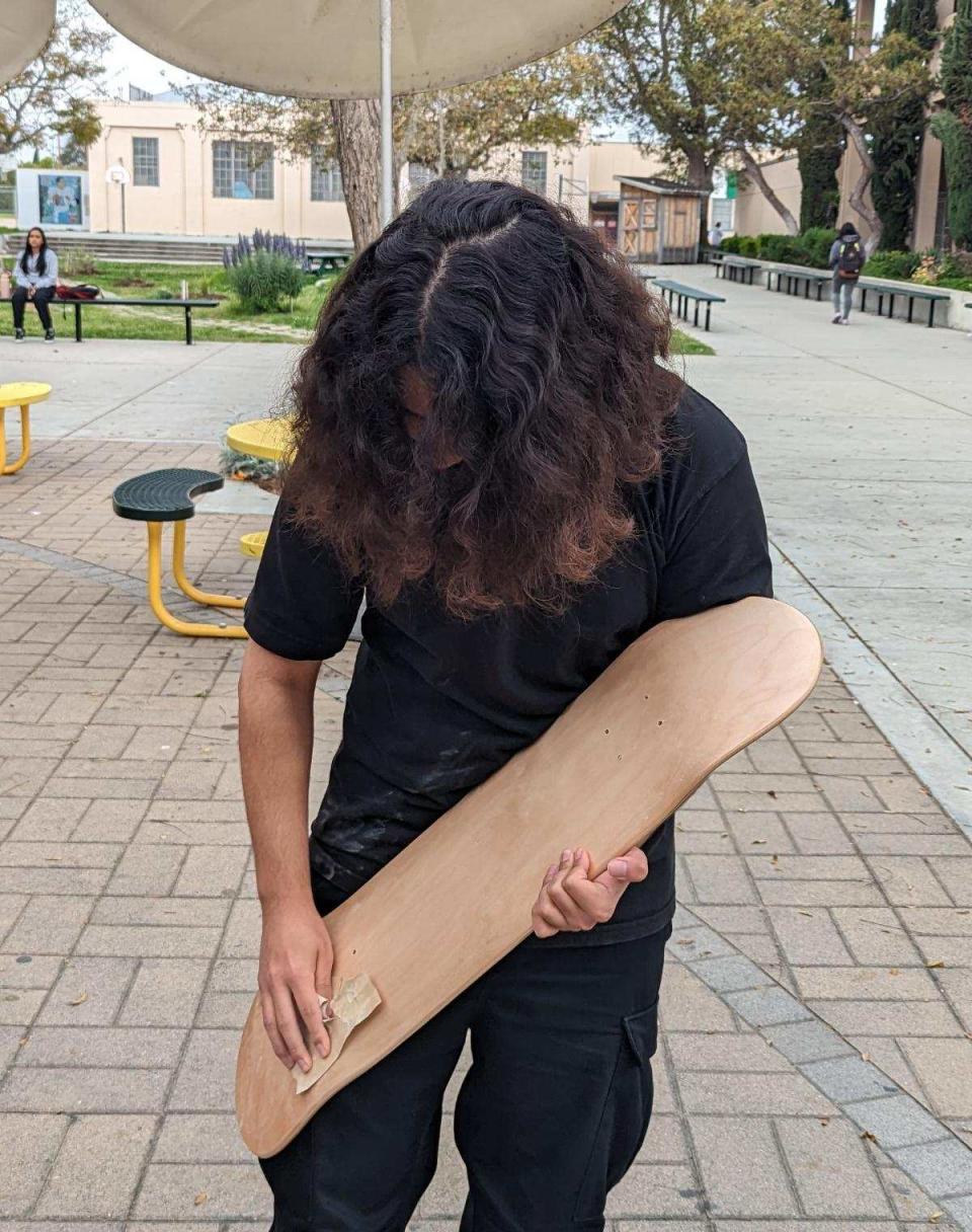 Alexander Hamilton High School student Kevin Gomez sands his blank skateboard in preparation for transferring his graphic design onto its surface as part of the Los Angeles school's Tyre Nichols Project.