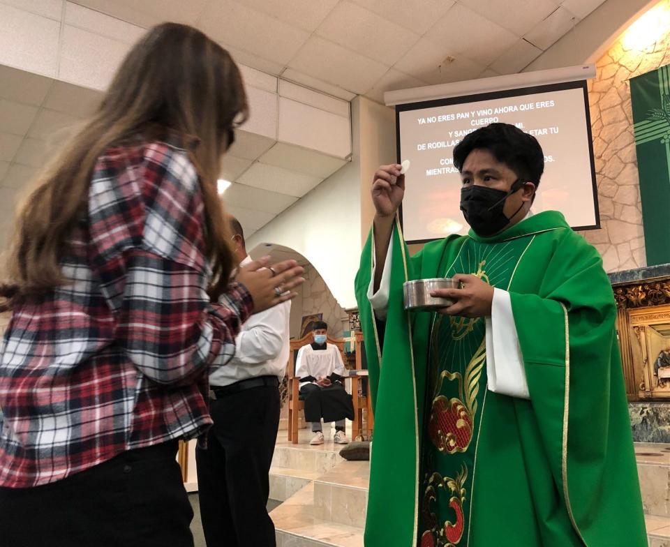 The Rev. Ryan Carnecer of Divine Providence Catholic Church in San Antonio hands out the sacrament during communion at Sunday mass. Carnecer has been active in getting his parishioners vaccinated against COVID-19. Latino Catholics lead most major religious groups in vaccination rates in the United States, according to recent studies.