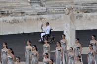 Beatrice Hess, France's greatest Paralympic champion, carries the Olympic flame during the flame handover ceremony at Panathenaic stadium, where the first modern games were held in 1896, in Athens, Friday, April 26, 2024. On Saturday the flame will board the Belem, a French three-masted sailing ship, built in 1896, to be transported to France.(AP Photo/Vasilis Psomas)