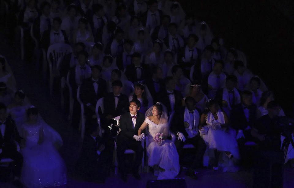 In this Monday, Aug. 27, 2018, file photo, a couple watches a screen during a mass wedding ceremony at the Cheong Shim Peace World Center in Gapyeong, South Korea. South Korean and foreign couples exchanged or reaffirmed marriage vows in the Unification Church's mass wedding arranged by Hak Ja Han Moon, wife of the late Rev. Sun Myung Moon, the controversial founder of the Unification Church. (AP Photo/Ahn Young-joon, File)