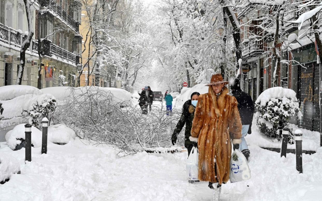 A woman wearing a fur coat walks amid a heavy snowfall in Madrid on January 9 - AFP