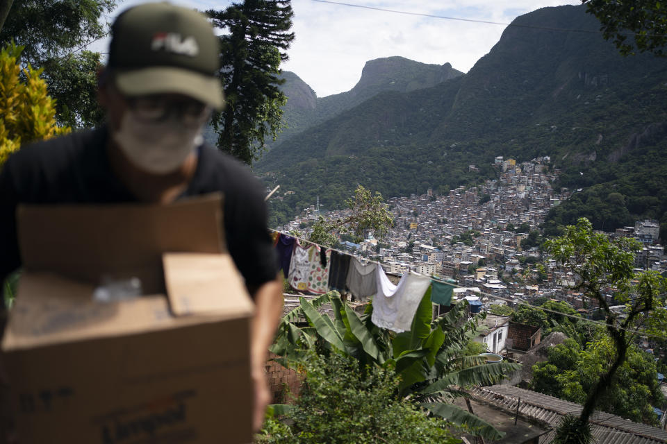 A local volunteer carries a package with soap and detergent to be distributed in an effort to stop the spread of the new coronavirus in the Rocinha slum of Rio de Janeiro, Brazil, Tuesday, March 24, 2020. (AP Photo/Leo Correa)