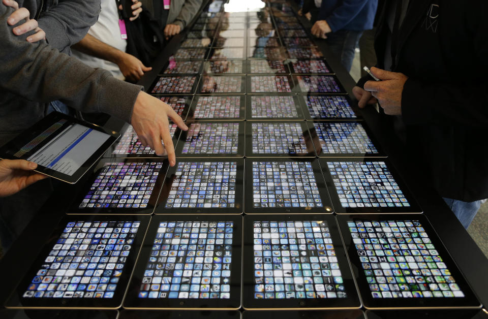 Developers look over new apps being displayed on iPads at the Apple Worldwide Developers Conference Monday, June 10, 2013 in San Francisco. (AP Photo/Eric Risberg)