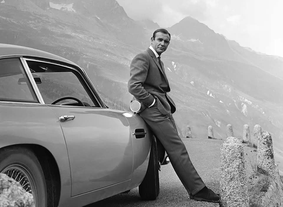 Sean Connery posiert in einer Szene aus „Goldfinger“ von 1964 als James Bond neben seinem Aston Martin DB5. (Michael Ochs Archives/Getty Images)