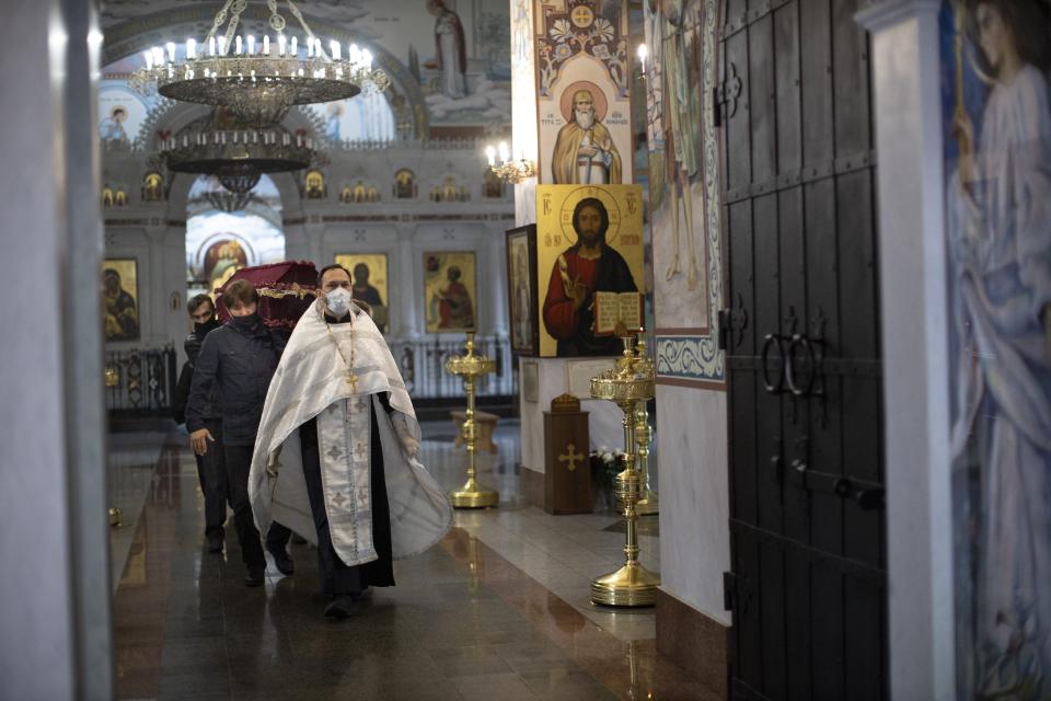 In this photo taken on Tuesday, June 2, 2020, Father Vasily Gelevan conducts a funeral service for a person who died of apoplexy at the Church of the Annunciation of the Holy Virgin in Sokolniki in Moscow, Russia. In addition to his regular duties as a Russian Orthodox priest, Father Vasily visits people infected with COVID-19 at their homes and hospitals. (AP Photo/Alexander Zemlianichenko)