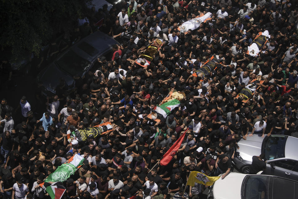 Mourners carry the bodies of Palestinian men killed during an Israeli military raid on the militant stronghold of the Jenin refugee camp in the West Bank, during their funeral, Wednesday, July 5, 2023. The Israeli army withdrew its forces early Wednesday, ending an intense two-day operation that killed at least 13 Palestinians, drove thousands of people from their homes and left a wide swath of damage in its wake. One Israeli soldier was also killed. (AP Photo/Nasser Nasser)