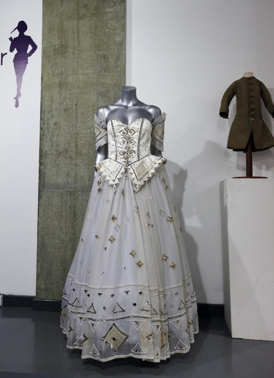 A 1986 Emanuel ball gown worn by late Princess Diana is displayed on a mannequin during an auction in London, Tuesday, Dec. 3, 2013. According to the auction house, Diana wore the gown with gold sequins, crystals and pearl beads comes with matching headband, optional sleeve panels and petticoat, in various occasions. (AP Photo/Lefteris Pitarakis)