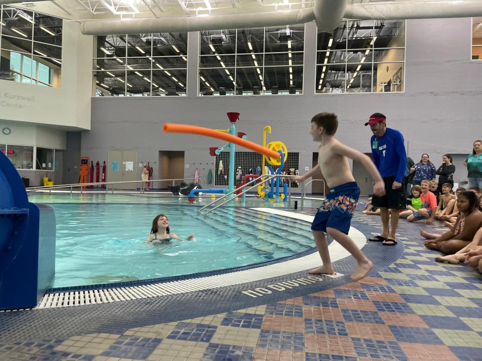 Charlie Doan, right, tosses a pool noodle to Baylee Russel, left, as part a water safety lesson at the YMCA on Nov. 17, 2023.