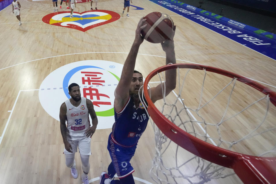 El centro serbio Nikola Milutinov (33) completa la volcada ante el puertorriqueño Christopher Ortiz (32) durante el partido de la Copa Mundial de basquetbol, el lunes 28 de agosto de 2023, en Manila. (AP Fto/Aaron Favila)