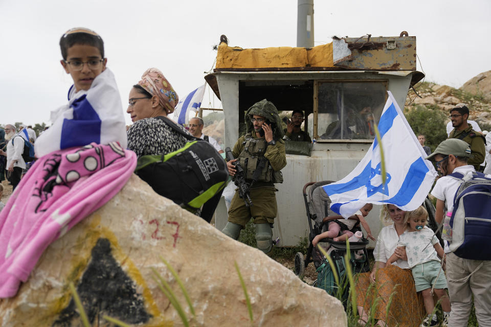 Israeli stand in outpost of Eviatar in the West Bank, Monday, April 10, 2023. Thousands led by hardline ultranationalist Jewish settlers marched to the unauthorized settlement outpost Eviatar in the northern West Bank that was cleared by the Israeli government in 2021, protected by a large contingent of Israeli soldiers and police. (AP Photo/Ariel Schalit)