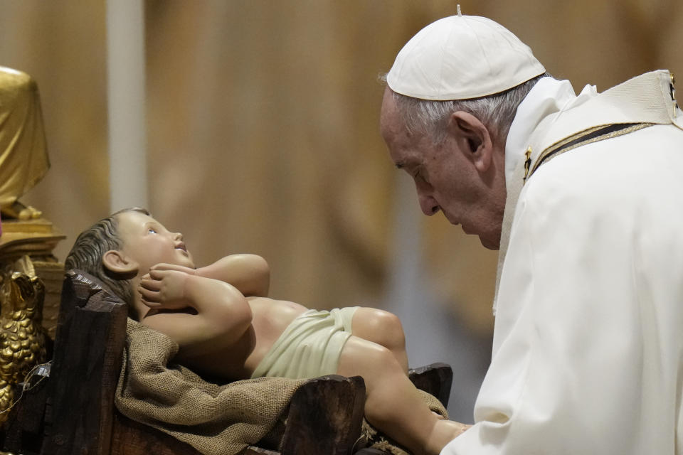 Pope Francis is about to kiss a statue of Baby Jesus as he celebrates Christmas Eve Mass, at St. Peter's Basilica, at the Vatican, Friday Dec. 24, 2021. (AP Photo/Alessandra Tarantino)