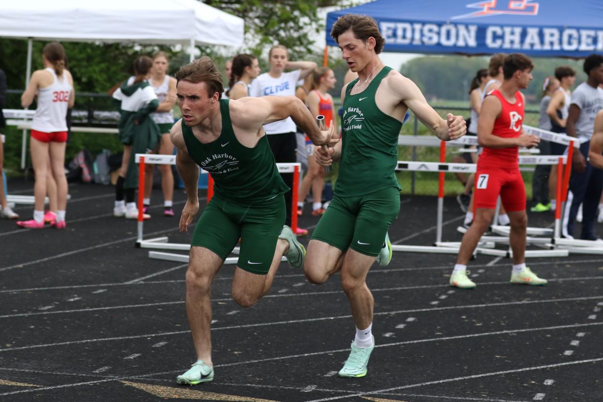 Oak Harbor's Hayden Buhro takes the baton from Wyatt Augsburger in the 4x100 relay.