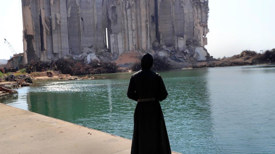 Ein Priester sieht im Hafen von Beirut auf die bei der Explosion vor einem Jahr zerstörten Getreidesilos. Viele Menschen verloren bei der Katastrophe ihr Leben.