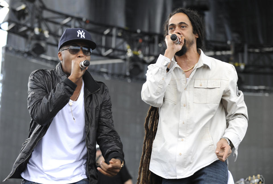 Nas and Damian Marley perform together on stage with microphones in thier hands.