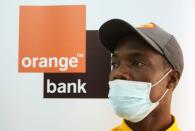 A security agent looks on while he stands at a bank of the French mobile operator Orange in Abidjan, Ivory Coas