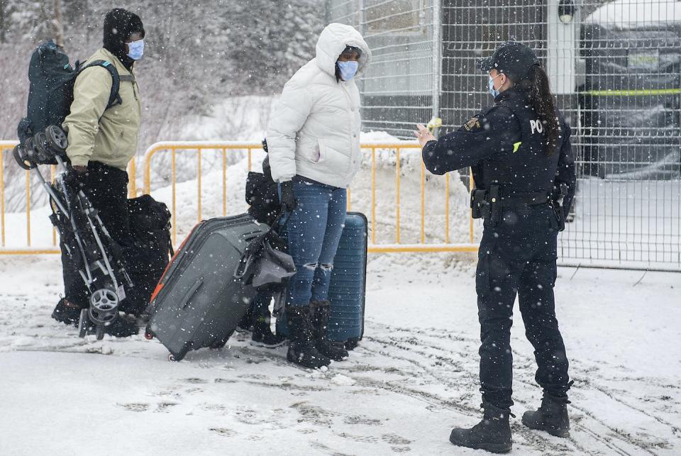 An RCMP officer stops people as they enter Canada via Roxham Road near Hemmingford, Que., hours after amendments to the Safe Third Country agreement enabled authorities to turn asylum-seekers away from unofficial border crossings. THE CANADIAN PRESS/Graham Hughes