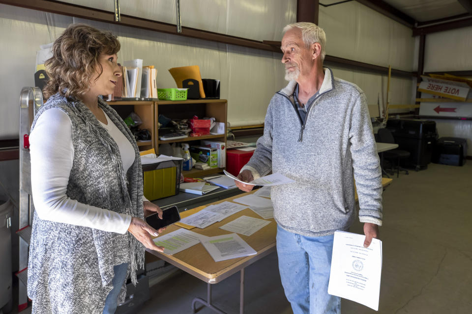 Torrance County manager Janice Barela, left, talks with Stephen Garrett, independent candidate for county commissioner, during a ballot-counting machines testing in Estancia, N.M., Sept. 29, 2022. (AP Photo/Andres Leighton)