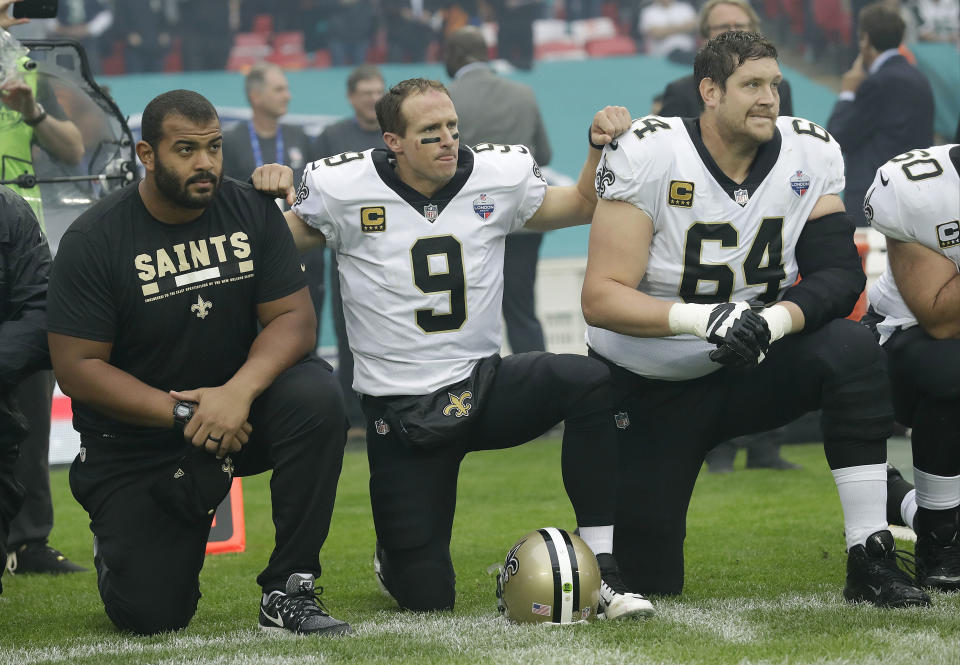 Saints quarterback Drew Brees (9) kneels down with teammates before the U.S. national anthem was played before New Orleans' game against Miami in London. (AP) 