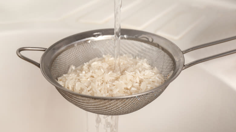 rice in sieve under tap