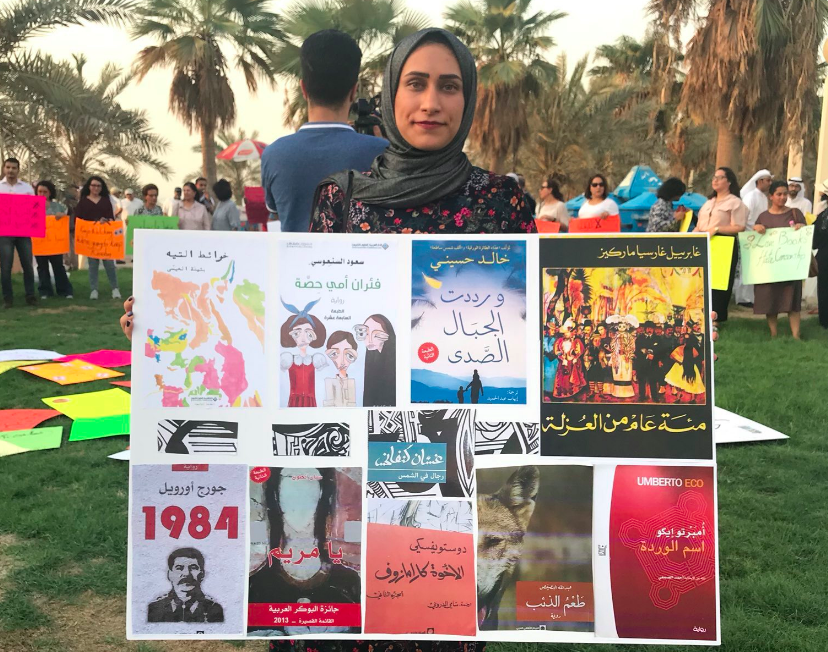 Mujer muestra libros censurados en protesta en Kuwait el 15 de septiembre. (Foto captura de pantalla @leanah_ )