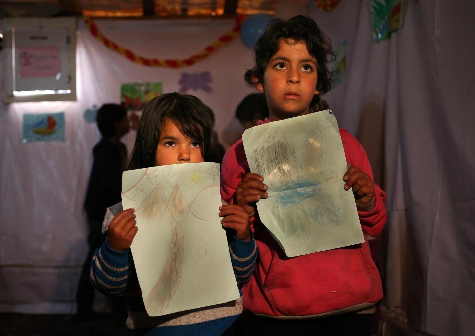 In this picture taken on Wednesday, March 12, 2014, Syrian refugee girls hold their paints as they wait to show them to their teacher inside a tent, a home for a refugee family that turns into a makeshift school in a refugee encampment in the Lebanese-Syrian border town of Majdal Anjar, eastern Bekaa valley, Lebanon. More than 2 million of those who should be in school remain in Syria, where classrooms have been bombed, used as shelters or turned into military barracks. Another 300,000 Syrian children don’t attend school in Lebanon, along with some 93,000 in Jordan, 78,000 in Turkey, 26,000 in Iraq and 4,000 in Egypt, UNICEF officials in Geneva said. Those numbers likely are higher, as UNICEF can’t count the children whose parents didn’t register with the United Nations refugee agency. (AP Photo/Hussein Malla)