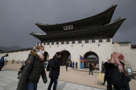 Visitors wearing face masks walk near the Gwanghwamun, the main gate of the 14th-century Gyeongbok Palace, and one of South Korea's well-known landmarks, in Seoul, South Korea, Saturday, Feb. 22, 2020. South Korea on Saturday reported a six-fold jump in viral infections in four days to 346, most of them linked to a church and a hospital in and around the fourth-largest city where schools were closed and worshipers and others told to avoid mass gatherings. (AP Photo/Lee Jin-man)