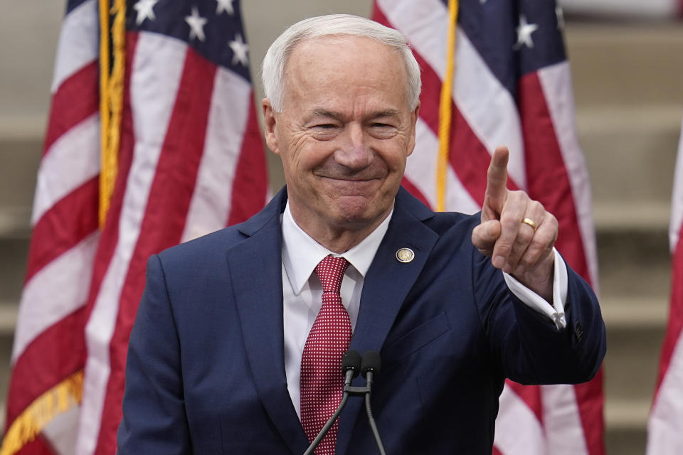 Asa Hutchinson stands at a podium, with American flags behind him.