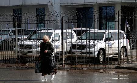 A woman walks past vehicles of the Organization for Security and Cooperation in Europe (OSCE) special monitoring mission for Ukraine parked near the OSCE office, in the pro-Russian rebel-held city of Luhansk, Ukraine, April 24, 2017. REUTERS/Alexander Ermochenko