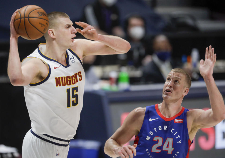 Denver Nuggets center Nikola Jokic (15) passes around Detroit Pistons center Mason Plumlee (24) in the first quarter of an NBA basketball game in Denver, Tuesday, April 6, 2021. (AP Photo/Joe Mahoney)