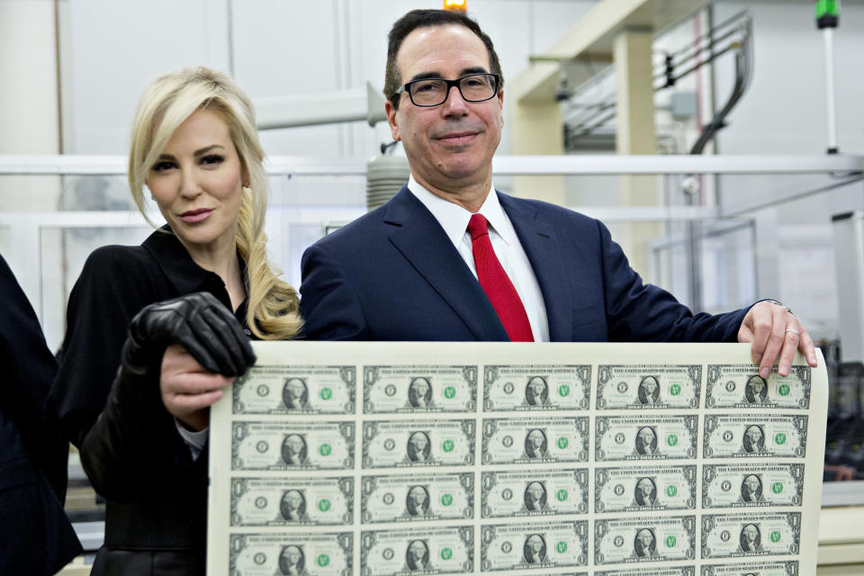 Treasury Secretary Steven Mnuchin and his wife, Louise Linton,&nbsp;pose on Wednesday holding a sheet of 50 $1&nbsp;bills bearing Mnuchin's name.