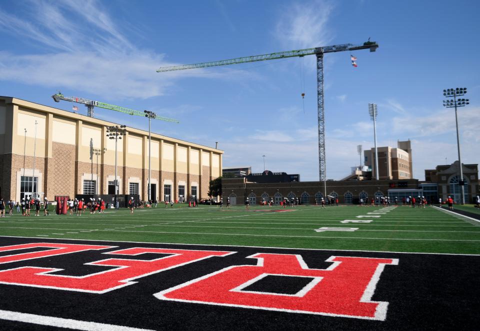 A construction crane at the south end of Jones AT&T Stadium overlooks the Texas Tech football practice fields outside the Sports Performance Center during the first day of practice on Friday. The construction project has narrowed the stadium capacity for this season to 56,200, more than 4,000 below normal capacity.