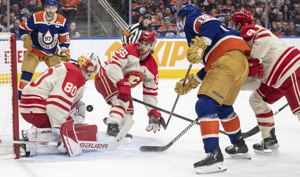 Calgary Flames goalie Dan Vladar (80) makes a save on Edmonton Oilers' Zach Hyman (18) as Noah Hanifin (55) defends during the second period of an NHL hockey game Saturday, Feb. 24, 2024, in Edmonton, Alberta. (Jason Franson/The Canadian Press via AP)