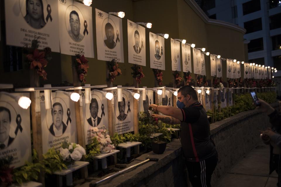 Javier Casana leaves flowers on the portrait of his uncle Jorge Luis Casana, 62, a doctor who died from COVID-19, in Lima, Peru, Tuesday, January 19, 2021. The Peruvian Medical College reported that at least 11 doctors have died during the first days of 2021. (AP Photo/Rodrigo Abd)