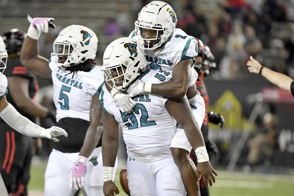 Coastal Carolina's C.J. Brewer (52) celebrates with Travis Geiger Jr. (5) and D'Jordan Strong (2) after making an interception against Arkansas State during the second half of an NCAA college football game Thursday, Oct. 7, 2021, in Jonesboro, Ark. (AP Photo/Michael Woods)