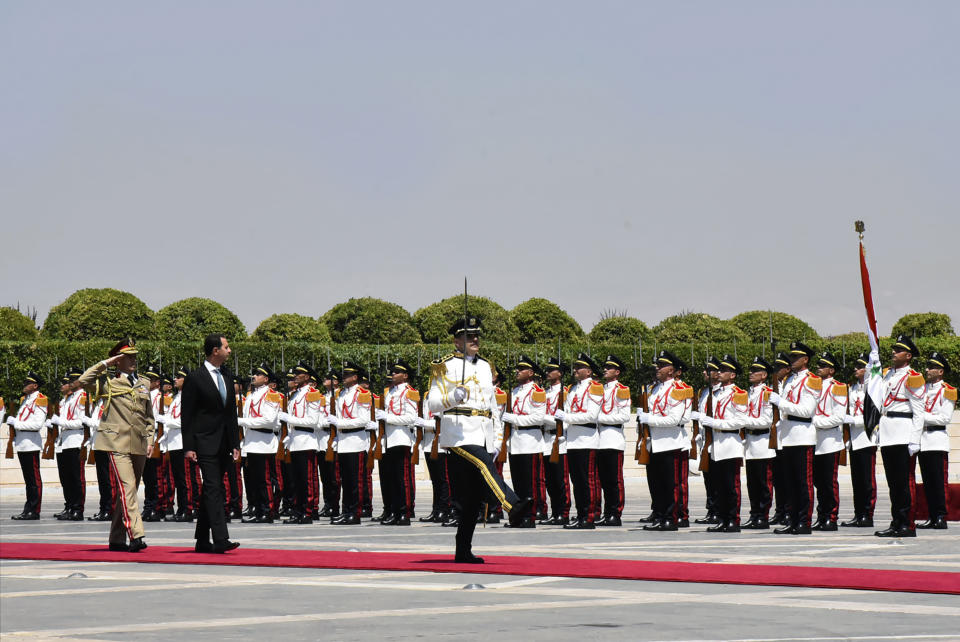 In this photo released by the official Facebook page of the Syrian Presidency, Syrian President Bashar Assad, second left, reviews an honor guard at the Syrian Presidential Palace in the capital Damascus, Syria, Saturday, July 17, 2021. In power since 2000, Assad's re-election in a landslide was not in doubt. His new term starts with the country still devastated by the 10-year war and sliding deeper into a worsening economic crisis. (Syrian Presidency via Facebook via AP)