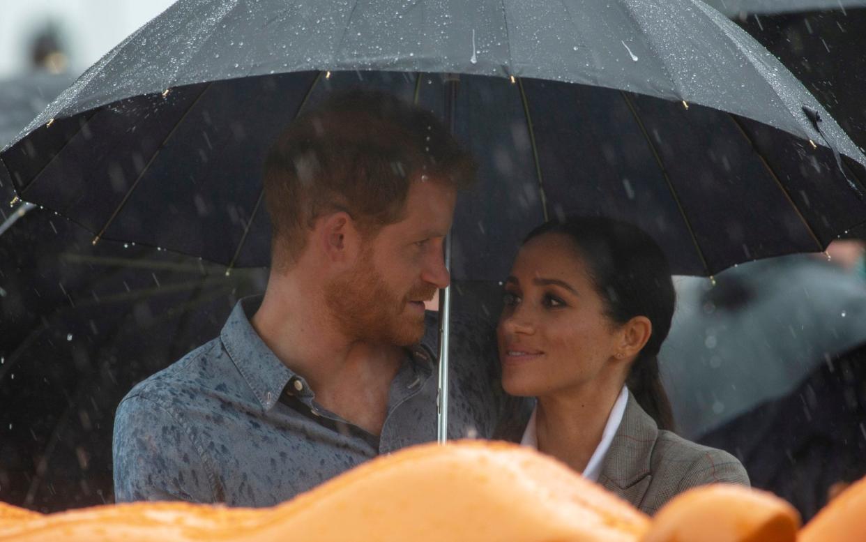 The Duke and Duchess of Sussex shelter from unexpected rain in Dubbo on the second day of their tour of Australia - Daily Mirror POOL