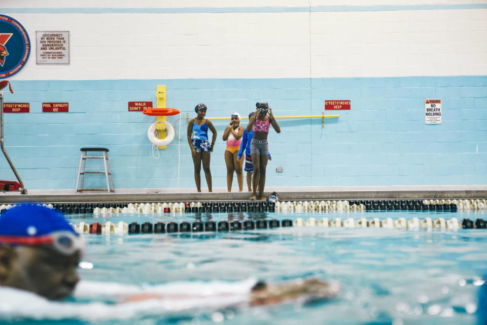 Girls stand by the pool and watch a swimmer (NBC News)