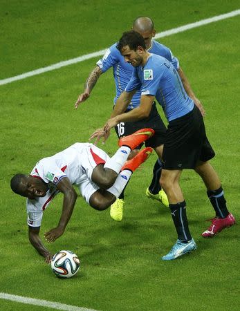 Costa Rica's Joel Campbell (L) is fouled by Uruguay's Maximiliano Pereira (back) next to teammate Cristian Rodriguez during their 2014 World Cup Group D soccer match at the Castelao arena in Fortaleza, June 14, 2014. REUTERS/Mike Blake