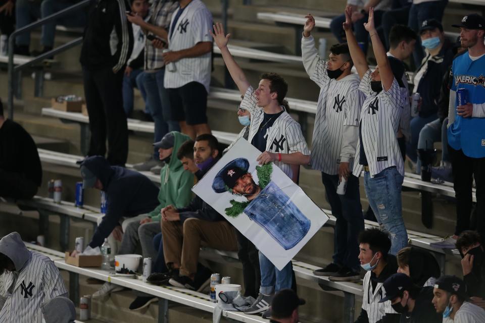 A New York Yankees fan holding a picture of Houston Astros second baseman Jose Altuve in a trash can reacts during the fifth inning at Yankee Stadium.