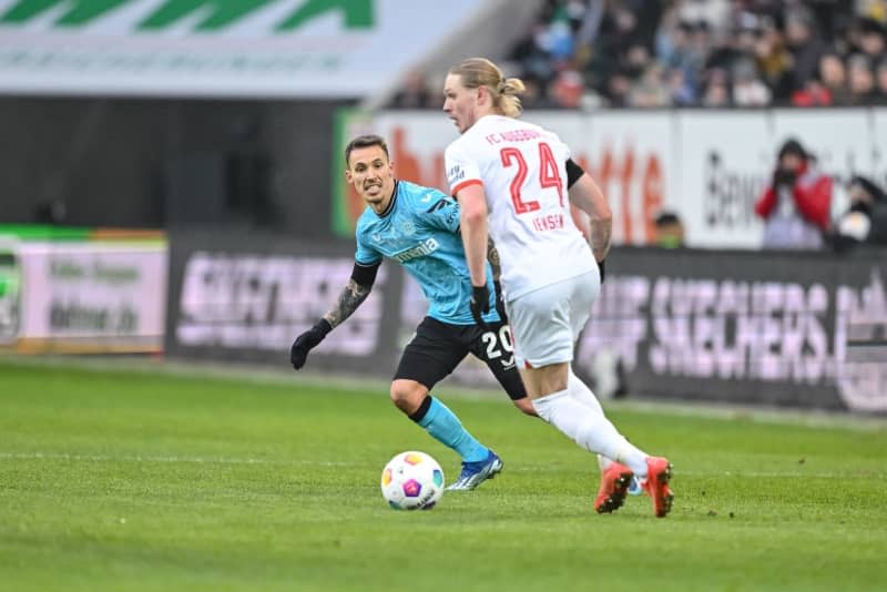 Leverkusen's Alejandro Grimaldo (L) and Augsburg's Fredrik Jensen (R) battle for the ball during the German Bundesliga soccer match between FC Augsburg and Bayer Leverkusen at the WWK Arena. Harry Langer/dpa