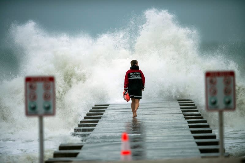 A lifeguard walks to the end of the jetty after closing it down to surfers before the arrival of Tropical Storm Eta in Bradenton Beach