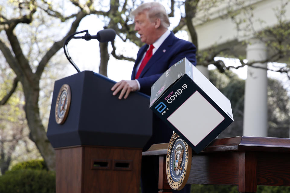 President Donald Trump speaks as a box containing a 5-minute test for COVID-19 from Abbott Laboratories blows off a table about the coronavirus in the Rose Garden of the White House, Monday, March 30, 2020, in Washington. (AP Photo/Alex Brandon)