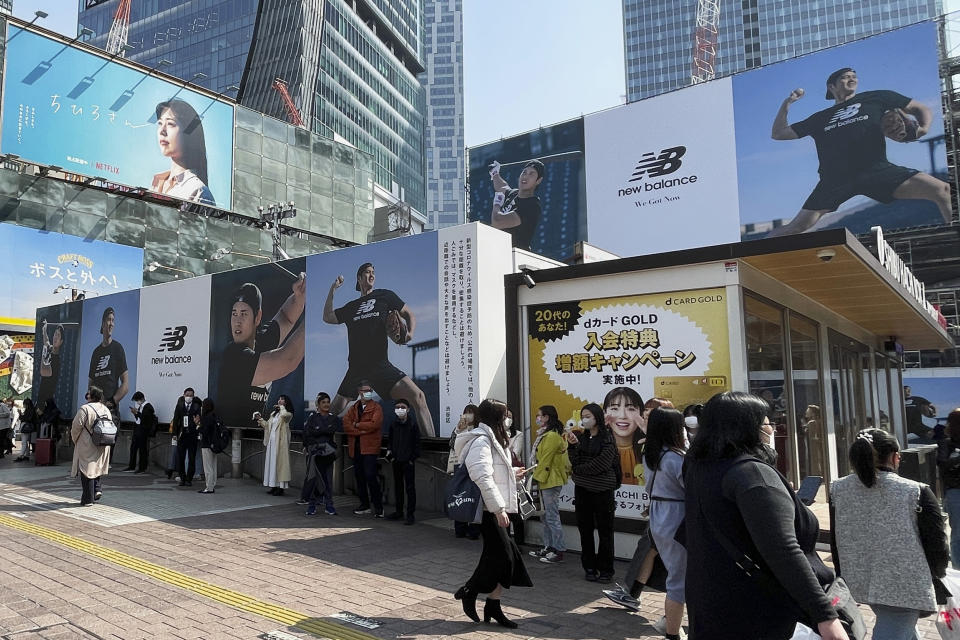 People stand by billboards showing pictures of baseball player Shohei Ohtani installed near a train station in the famed Shibuya shopping district in Tokyo on Thursday, March 9, 2023. Japanese baseball player Shohei Ohtani is arguably the game's best player. But he's more than just a baseball player. He's an antidote for many in his native country. (AP Photo/Haruka Nuga)