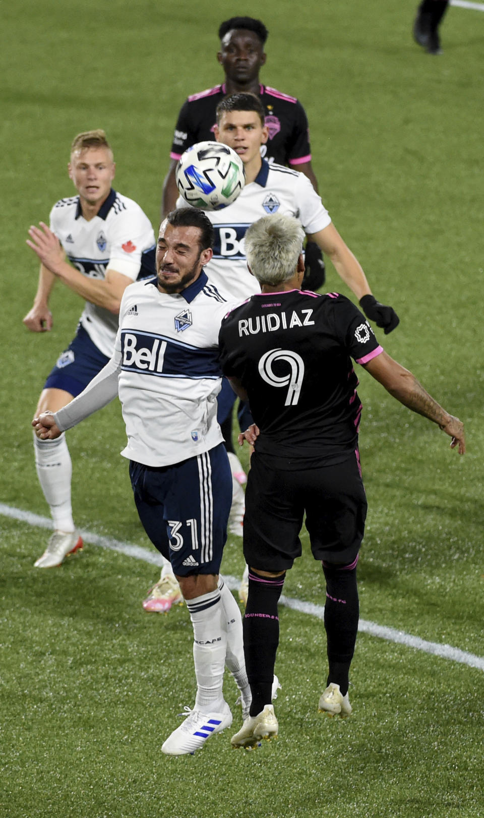 Vancouver Whitecaps midfielder Russell Teibert, left, and Seattle Sounders forward Raul Ruidiaz jump for a head ball during the first half of an MLS soccer match in Portland, Ore., Tuesday, Oct. 27, 2020. (AP Photo/Steve Dykes)