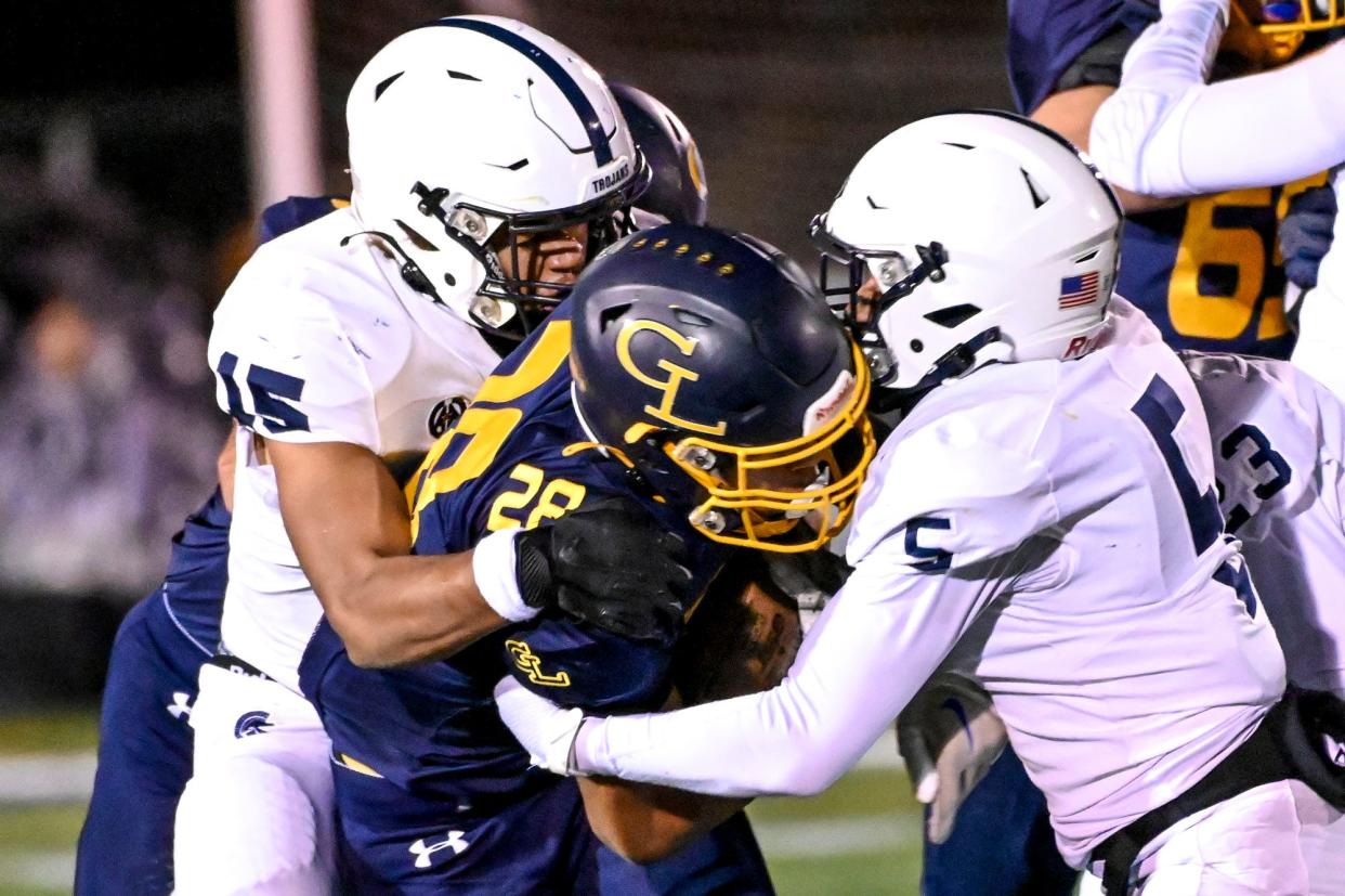 East Lansing's Dontaveus Royals, left, and Julius Goodwin, right, tackle Anthony Baker during the second quarter on Friday, Oct. 20, 2023, at Grand Ledge High School.