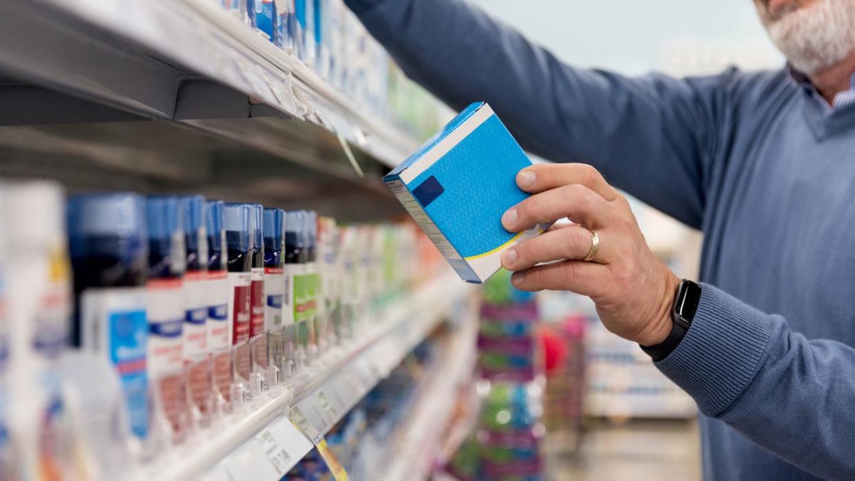 unrecognizable mature man reads medication instructions at pharmacy