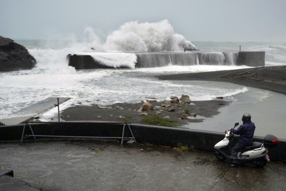 A man on a scooter watches as surging waves hit against the breakwater as Typhoon Hagibis approaches a port in Kumano, Mie Prefecture, Japan, Saturday, Oct. 12, 2019. (AP Photo/Toru Hanai)