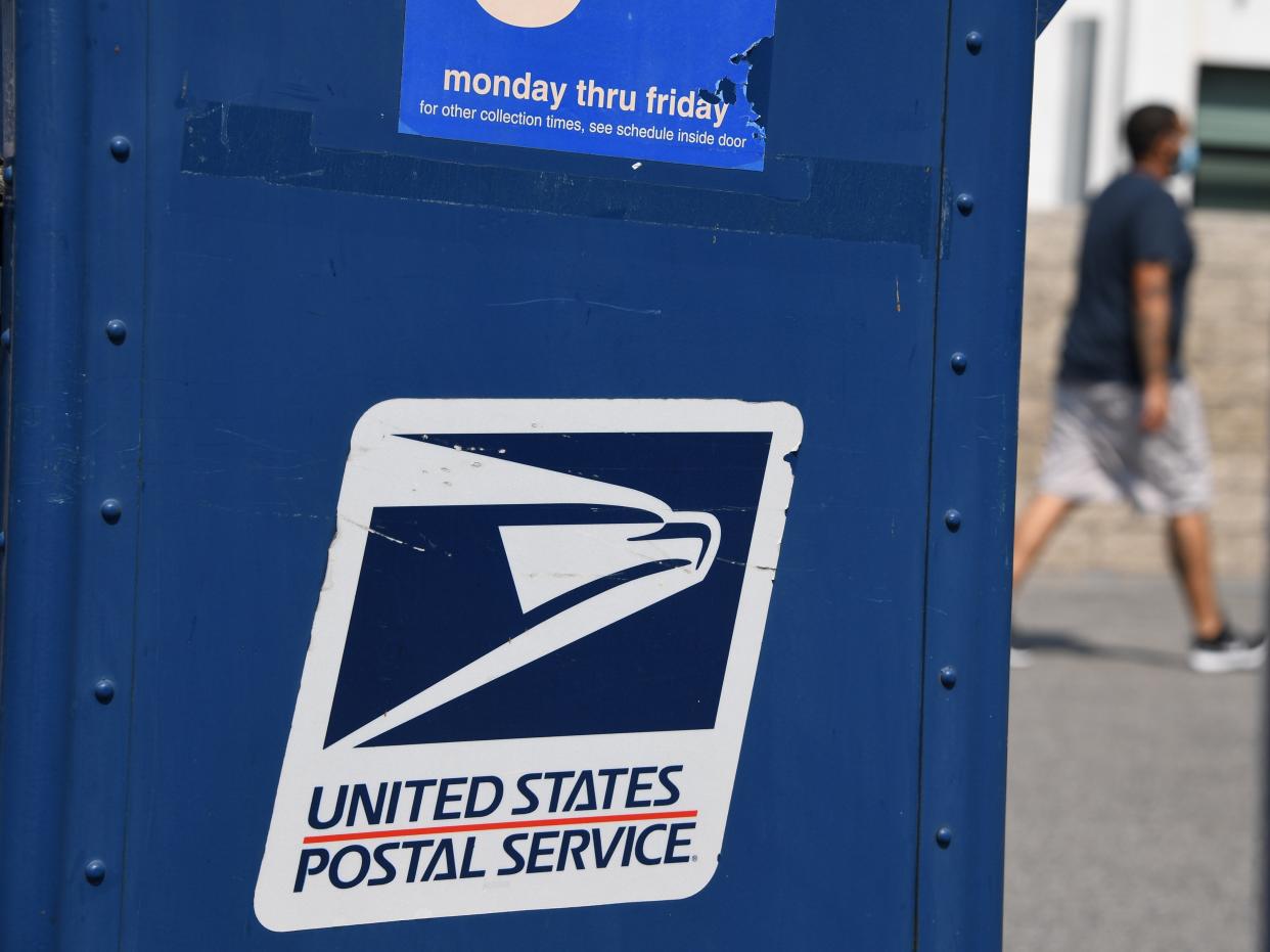 <p>A man walks past a mail box outside a post office in Los Angeles, California on 17 August 2020</p> ((AFP via Getty Images))